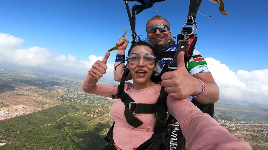 Tandem skydiving participant securely attached to an instructor above the Diani coastline